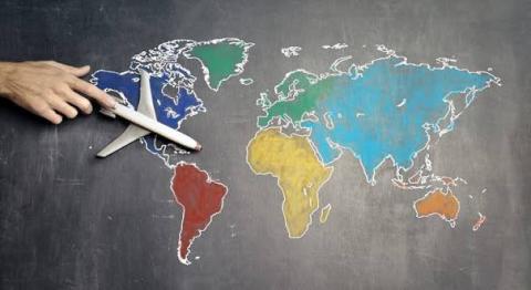 Une main déplace un avion sur le planisphère. 